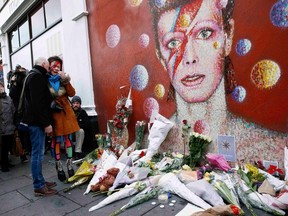 A woman wearing Ziggy Stardust style make-up reacts as she visits a mural of David Bowie in Brixton, south London, January 11, 2016. David Bowie, a music legend who used daringly androgynous displays of sexuality and glittering costumes to frame legendary rock hits "Ziggy Stardust" and "Space Oddity", has died of cancer.  REUTERS/Stefan Wermuth