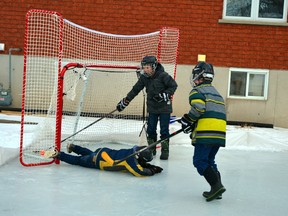 On a backyard ice rink last Friday afternoon, Jan. 8, Lucas Roobroeck slips and falls, yet still manages to score on net because Jake Crowley is laughing too hard to bother to make the save while Noah Mann rushes in to join the fun. GALEN SIMMONS/MITCHELL ADVOCATE