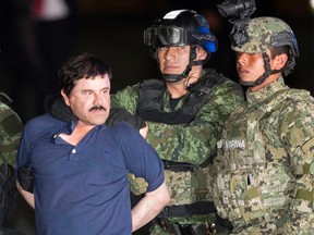 In this Friday, Jan. 8, 2016 photo, Joaquin "El Chapo" Guzman is made to face the press as he's escorted to a helicopter in handcuffs by soldiers and marines at a federal hangar in Mexico City. (AP Photo/Eduardo Verdugo)