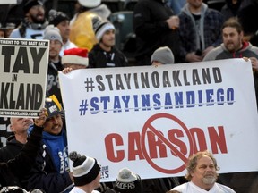 Spectators hold signs reading "Stay in Oakland" and "Stay in San Diego" in reference to the Chargers and Raiders proposed move to Los Angeles during the Raiders game against the Chargers at Oakland Coliseum on Dec. 25, 2015. (Kirby Lee/USA TODAY Sports/Files)