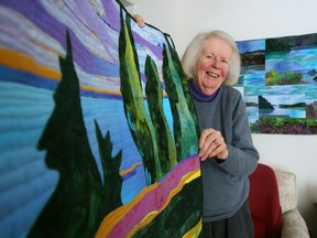 Luke Hendry/The Intelligencer
Artist Joan Reive holds one of her art quilts at her home in Bayside Tuesday. Entitled "A Fall Day in Westport," it is part of a national touring show organized by non-profit group Studio Art Quilts Associates. At right is "Lake Vistas II," her entry in the group's international show.