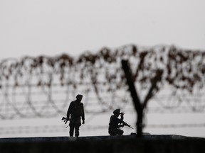 In this Jan. 6, 2016 file photo, Indian soldiers keep guard at the perimeter fence of the Indian air force base in Pathankot, India. (AP Photo/Channi Anand, File)