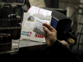 A customer purchases a Powerball lottery ticket at a news stand on Wall St. in New York January 13, 2016. Dreams of quitting an uninspiring job, helping the needy and traveling the world opened American wallets on Wednesday for a chance to win the biggest-ever $1.5 billion Powerball lottery jackpot. REUTERS/Brendan McDermid