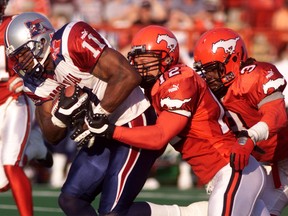 Montreal’s Lawrence Phillips (11) drags Calgary Stampeders safety Greg Frers (12) and defensive back Kelly Malveaux (3) for a first down July 18, 2002 in Calgary. (REUTERS/Patrick Price)