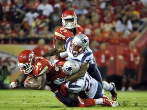 Kansas City Chiefs running back Knile Davis is tackled by New England Patriots cornerback Darrelle Revis and defensive back Malcolm Butler in the second half at Arrowhead Stadium in Kansas City on Sept. 29, 2015. (John Rieger/USA TODAY Sports)