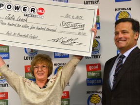In this Oct. 6, 2015 file photo, Julie Leach of Three Rivers, Mich., holds her $310 Million Powerball jackpot cheque, accompanied by Michigan Lottery Commissioner M. Scott Bowen in Lansing, Mich. Even an eye-popping jackpot isn’t enough to buy anonymity for many lottery winners, whose names are often made public by state law. But now it’s becoming increasingly possible for big winners to hide their identity, and lottery executives are trying to strike a balance between ensuring privacy and safety while still proving to the public that real people can win. (Dale G. Young/The Detroit News via AP, File)