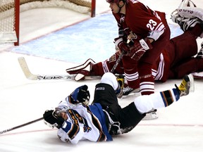 In this Jan. 16, 2006 file photo, Capitals winger Alex Ovechkin (front) shoots the puck from over his head after being checked to the ice by Coyotes defenceman Paul Mara (centre) past Coyotes goalie Brian Boucher for a goal in the third period in Glendale, Ariz. (Paul Connors/AP Photo/Files)
