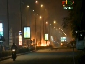 A motorcyclist rides along a road while fire and smoke rising from Splendid Hotel in Ouagadougou where suspected Islamist fighters are holding hostages in this still image from a video grab, January 15, 2016. Security forces in Burkina Faso battled suspected Islamist fighters outside the hotel in the capital's business district on Friday, gendarmes and witnesses sources said. (REUTERS/RTB via REUTERS TV)