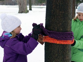 Sisters Alexie, on left, and Roxanne Walsh, students from Ecole Monseigneur-Remi-Gaulin tie scarves they've knitted for the less-fortunate at City Park in Kingston, Ont. on Saturday January 16, 2016. Steph Crosier/Kingston Whig-Standard/Postmedia Network