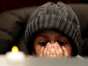 A young boy listens to speeches during a candlelight vigil in council chambers for GTA pastor Hyeon Soo Lim, who's being held in North Korea. 
(Craig Robertson/Toronto Sun/Postmedia Network