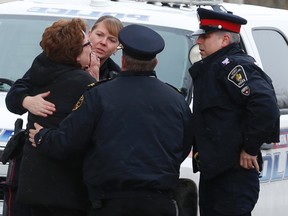 Police officers console an unidentified woman outside the Eagle St. seniors building where a woman died in a fire. (JACK BOLAND, Toronto Sun)