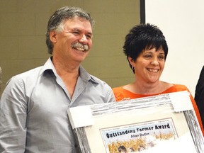 Allan Butler holds an award with his wife Kathy after being named Outstanding Farmer of the Year at the Lambton Soil and Crop Improvement Association’s annual meeting. (Brent Boles/ Postmedia Network)