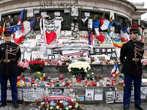 French honour guards stand next to the monument at Place de la Republique in Paris, where people laid candles cards and flags during a ceremony to honour the victims of the Islamic extremist attacks at at Place de la Republique in Paris, Sunday, Jan. 10, 2016. (Yoan Valat, via AP Pool)