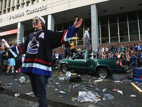 A Vancouver Canucks fan poses for photos in front of a destroyed pickup truck during a riot after the Canucks lost Game 7 of the NHL Stanley Cup playoffs to the Boston Bruins in Vancouver, British Columbia June 15, 2011. (REUTERS/Anthony Bolante)