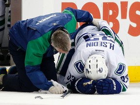 A trainer examines Vancouver Canucks center Henrik Sedin in the first period of an NHL hockey game against the New York Islanders in New York on Jan. 17, 2016. (AP Photo/Kathy Willens)