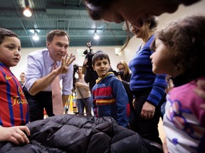 Finance Minister Bill Morneau plays the numbers game while trying to guess the age of Alma al Saiah, 4, at right in pink, at Central Neighbourhood House, a Syrian Refugee Welcome Centre in Toronto on Wednesday, January 13, 2016. (THE CANADIAN PRESS/Peter Power)