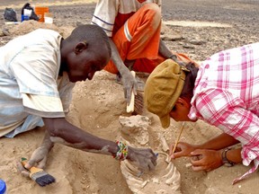 In this August 2012 photo provided by Marta Mirazon Lahr, researcher Frances Rivera, right, Michael Emsugut, left, and Tot Ekulukum excavate a human skeleton at the site of Nataruk, West Turkana, Kenya. (Marta Mirazon Lahr via AP)