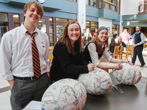 It's the week before exams and Caleb Stringer, left, Gabriella Hubbard and Maggie Drolet, write a few bad habits they want to bust onto some paper mache pinatas as part of the school's student mental health ambassadors 'Beat the Exam Blues' week activities to help students deal with mental and physical stresses of exams at Regiopolios Notre Dame Catholic Secondary School. (Julia McKay/The Whig-Standard)