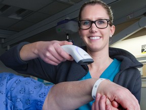 Registered nurse Ashlyn Renkema demonstrates the patient bar code scanner at London Health Sciences Centre. (DEREK RUTTAN, The London Free Press)