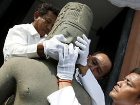 The head belonging to the Harihara statue is reattached to its body by museum employees during a ceremony at Cambodia's National Museum in Phnom Penh January 21, 2016. French museum Guimet handed over the head of the Harihara statue, which was looted from its temple in Takeo province 130 years ago, to the Cambodian government on January 16, 2016, according to media reports. REUTERS/Samrang Pring