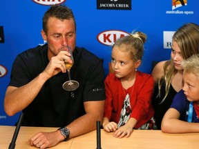 Australia's Lleyton Hewitt drinks champagne during a news conference while his children, Ava (2nd L-R), Mia and Cruz, watch after playing his last Australian Open singles match before his retirement, at the Australian Open tennis tournament at Melbourne Park, Australia, January 21, 2016. REUTERS/Issei Kato