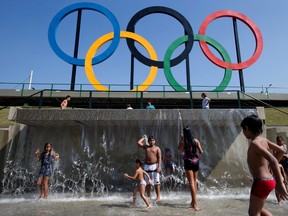 In this July 28, 2015 file photo, children play in a water fountain next to Olympic rings at Madureira Park in Rio de Janeiro, Brazil. Facing severe budget cuts in almost all aspects of the games, the Rio de Janeiro Olympics will get a boost from Japanese electronics company Panasonic, which has signed on as "Official Ceremony Partner."(AP Photo/Silvia Izquierdo, File)