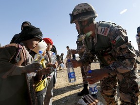 A Jordanian soldier gives food and water to Syrian refugees after they crossed into Jordanian territory with their families, near the town of Ruwaished, in the Hadalat area, east of the capital Amman, on Jan. 14. After months of being stranded at the border, a group of Syrian refugees is finally allowed to enter Jordan. Jordanian authorities say they have to address security concerns before allowing more refugees into the country burdened with more than 1.4 million refugees, said the commander of Jordan's border guard force, Brig.-Gen. Saber Mahayrah.