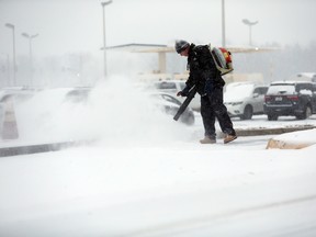 George Morris, with Standard Parking, works on clearing an entrance to airport parking as snow falls Friday morning, Jan. 22, 2016, in Roanoke, Va. Airlines have canceled more than 2,700 flights Friday to, from or within the U.S., as a blizzard swings up the East Coast, according to flight tracking service FlightAware. (Stephanie Klein-Davis/The Roanoke Times via AP)