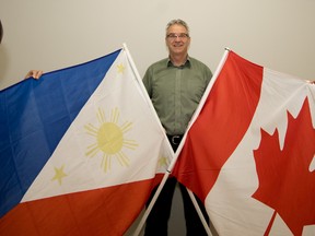 Pastor Roc Weigl and his parishioners Grace Delamerced, left, and Amy Bugera hold up the Philippines and Canadian flags to celebrate their upcoming mission to the Philippines, at the Stony Plain Baptist Church in Stony Plain on Monday, Jan. 11. Weigl and his parishioners have raised enough money to start building a church in the village of Balanti, Philippines, and will travel there at the end of January to oversee construction. - photo by Yasmin Mayne