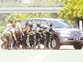 Police officers take cover behind a vehicle during a gun battle with Islamist attackers in Jakarta, Indonesia on Jan. 14. (AP Photo)