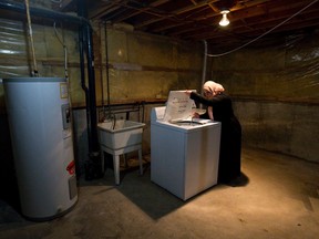 London Cross Cultural Learner Centre housing co-ordinator Perihan El Shamy examines a second-hand washing machine in the basement of a unit on Upper Queens Avenue recently occupied by a Syrian refugee family, the Ghozlans. (CRAIG GLOVER, The London Free Press)