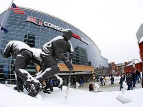 Snow covers a statue of Pittsburgh Penguins Hockey Hall of Famer Mario Lemieux outside the Consol Energy Center before a game between the Penguins and Vancouver Canucks in Pittsburgh, Saturday, Jan. 23, 2016. (AP Photo/Gene J. Puskar)