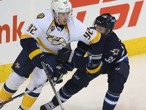 Ryan Johansen, shown here being checked by Jets defenceman Toby Enstrom during a game in Winnipeg on Thursday, has nine points in seven games since being traded to the Predators. (Brian Donogh)