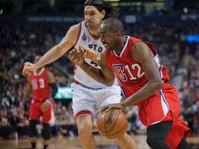 Los Angeles Clippers forward Luc Mbah a Moute (12) dribbles past Toronto Raptors forward Luis Scola (4)  in the first quarter at Air Canada Centre. Peter Llewellyn-USA TODAY Sports