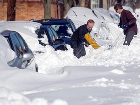People dig out their cars in Alexandria, Va., Sunday, Jan. 24, 2016. Millions of Americans were preparing to dig themselves out Sunday after a mammoth blizzard with hurricane-force winds and record-setting snowfall brought much of the East Coast to an icy standstill. (AP Photo/Cliff Owen)