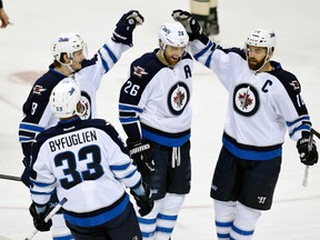 Winnipeg Jets' Dustin Byfuglien (33), Jacob Trouba (8) and Andrew Ladd (16) congratulate right wing Blake Wheeler (26) on a goal against the Minnesota Wild during the first period of an NHL hockey game Friday, Jan. 15, 2016, in St. Paul, Minn.