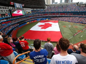 A giant Canadian flag covers the field at Rogers Centre during the playing of O Canada before a Blue Jays' Canada Day game in 2013. (Craig Robertson/Toronto Sun)