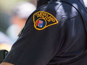 A Cleveland police officer looks on as people take to the streets and protest in reaction to Cleveland police officer Michael Brelo being acquitted of manslaughter charges after he shot two people at the end of a 2012 car chase in which officers fired 137 shots May 23, 2015 in Cleveland, Ohio. (Ricky Rhodes/Getty Images/AFP)