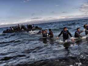 Refugees and migrants arrive on dinghies at the Greek island of Lesbos, after crossing the Aegean sea from Turkey on October 2, 2015. (AFP PHOTO/ARIS MESSINIS)