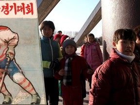 North Korean children walk past a standing signboard depicting ice hockey in Pyongyang, North Korea, in this undated handout picture. A Canadian man behind a series of trips to North Korea by basketball hall of famer Dennis Rodman is organising an ice hockey tournament that may draw former National Hockey League (NHL) players to the isolated country.  (REUTERS/Michael Spavor/Handout via Reuters)