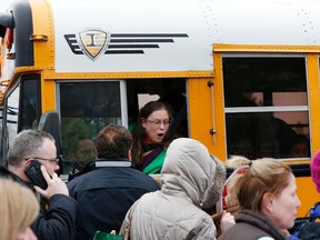 A school bus driver yells to a parent that their child is safe after a bus accident at Amy Beverland Elementary School left several students injured and one adult dead on school grounds on Jan. 26, 2016, in Indianapolis. Authorities say a bus waiting outside the Indianapolis elementary school suddenly lurched forward and struck them. (Mykal McEldowney/The Indianapolis Star via AP)