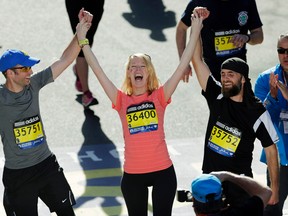 In this April 21, 2014 file photo, Timothy Haslet, left, and David Haslet, right, celebrate with their sister Adrianne Haslet-Davis at the finish line of the 118th Boston Marathon, after she completed a short distance of the course in Boston. Haslet-Davis said she is training to run the entire Boston Marathon on April 18, 2016. Haslet-Davis lost her left leg below the knee in the April 2013 bombing attacks, which killed three people and wounded more than 260 others. (AP Photo/Charles Krupa, File)