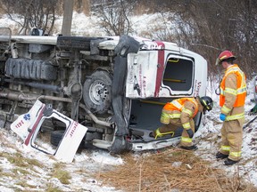 A firefighter climbs out of an overturned Voyageur patient transfer van following a three-vehicle collision that shut down a section of northbound Highbury Avenue at Bradley Avenue around noon in London on Jan. 27. (Free Press file photo)