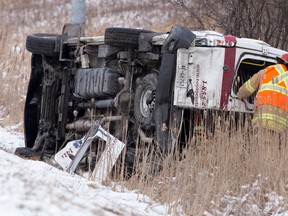 A firefighter looks in the rear window of an overturned Voyageur patient transfer van following a three-vehicle collision that shut down a section of northbound Highbury Avenue at Bradley Avenue around noon in London, Ont. on Wednesday January 27, 2016. Five occupants from the van were taken to hospital, two with serious injuries, according to police.  The incident is under investigation.  Craig Glover/The London Free Press/Postmedia Network