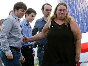 In this Sept. 2, 2015 file photo, Melodie Gliniewicz, the wife of Fox Lake Police Lt. Charles Joseph Gliniewicz, leaves with her family during a vigil to honour her husband in Fox Lake, Ill. Authorities later said Gliniewicz staged his suicide to look like a homicide after embezzling from a youth program. On Wednesday, Jan. 27, 2016, a grand jury indicted Melodie Gliniewicz on felony counts of money laundering and disbursing charitable funds without authority for personal benefit. (AP Photo/Nam Y. Huh, File)