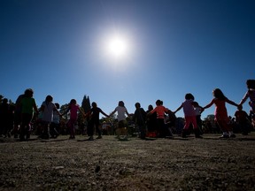 Children hold hands as students and teachers from Britannia Secondary School and Britannia Elementary School participate in a First Nations drum circle to coincide with the Youth Matters conference in Vancouver, B.C., on Tuesday, Sept. 29, 2015.
