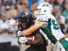 Ottawa Redblacks’ Chevon Walker (left) is tackled by Saskatchewan Roughriders defensive lineman John Chick in Ottawa August 2, 2014. (REUTERS/Chris Wattie)