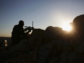 In this Nov. 12, 2015, file photo, a Kurdish peshmerga fighter stands guard in fighting against the Islamic State group as the sun rises in Sinjar, Iraq. (AP Photo/Bram Janssen, File)