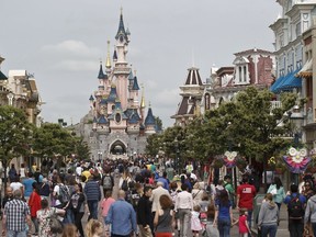 This May 12, 2015 file photo, shows visitors walking toward Sleeping Beauty's Castle, background, at Disneyland Paris in Marne la Vallee, east of Paris, France. A French police official says a man found to be carrying two handguns has been arrested at a hotel at Disneyland Paris. (AP Photo/Michel Euler, File)