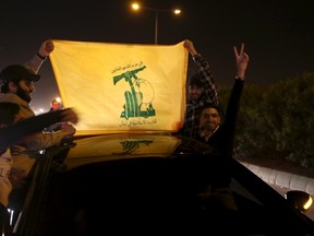 Hezbollah supporters hold a Hezbollah flag as they ride in a convoy waiting for the arrival of planes from Turkey carrying fighters and civilians from the two besieged Shi'ite towns of al-Foua and Kefraya, at Beirut's airport road, Lebanon December 28, 2015. REUTERS/Aziz Taher